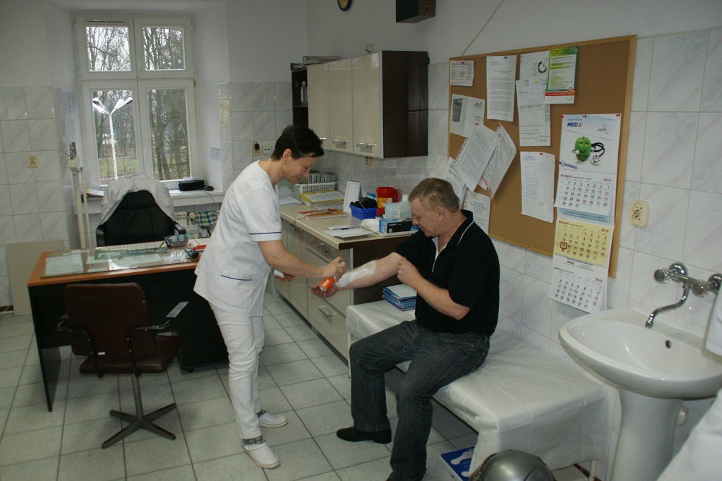 Pielęgniarka, zmienia opatrunek mieszkańcowi w gabinecie Domu Pomocy Społecznej w Psarach.